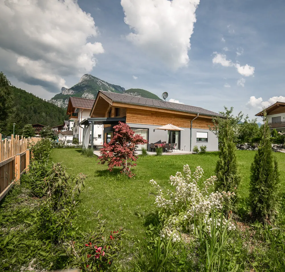 Sommerlicher Garten mit Blumen und Blick auf das Haus Wildmoos
