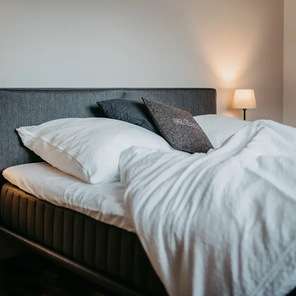 Doppelbett mit weißer Bettwäsche und Nachttischlampe – gemütlich & ruhig