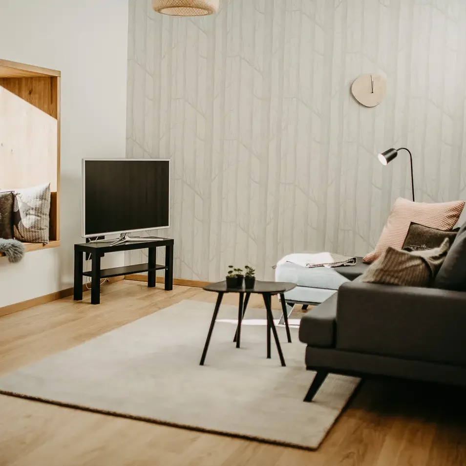Gemütliches Wohnzimmer mit TV, Couch und Holzelementen